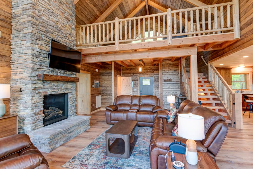 Great room with charming fireplace and rustic loft space visible in background