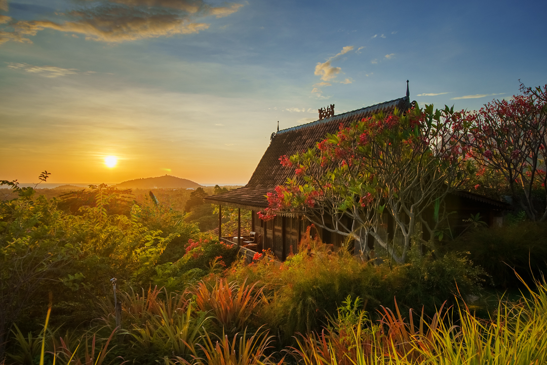 Traditional wooden house at sunrise with tropical plants and scenic view