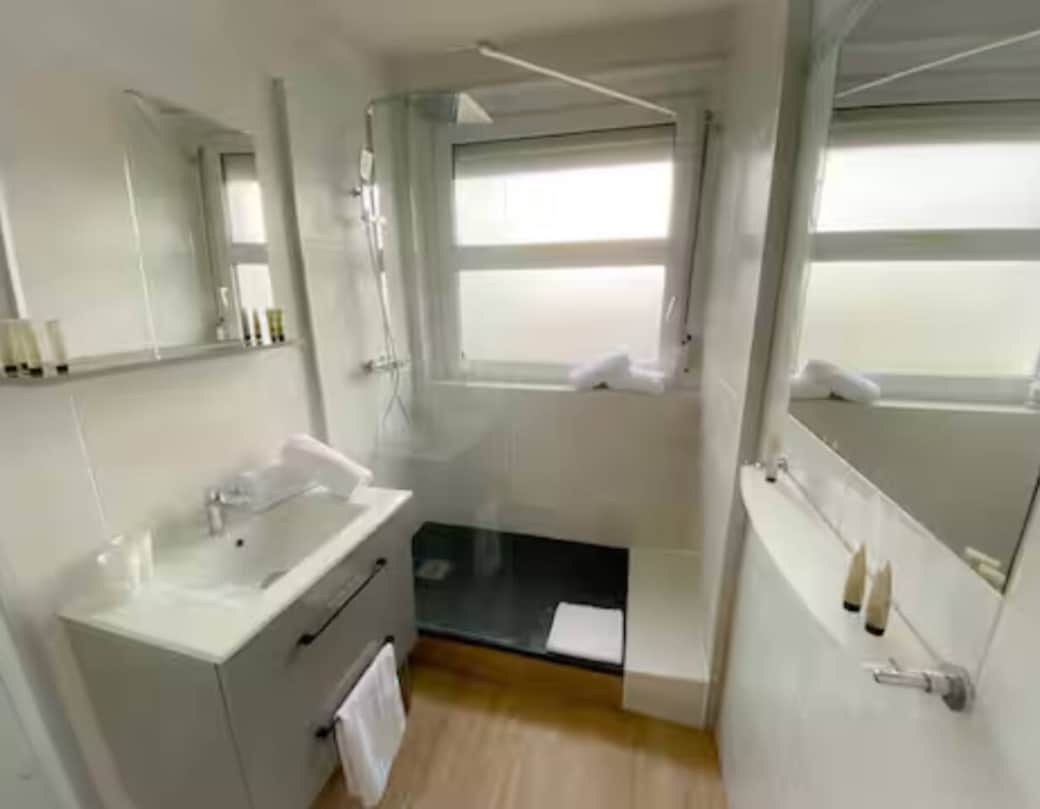 Salle de bain moderne avec douche, WC et sèche-cheveux.