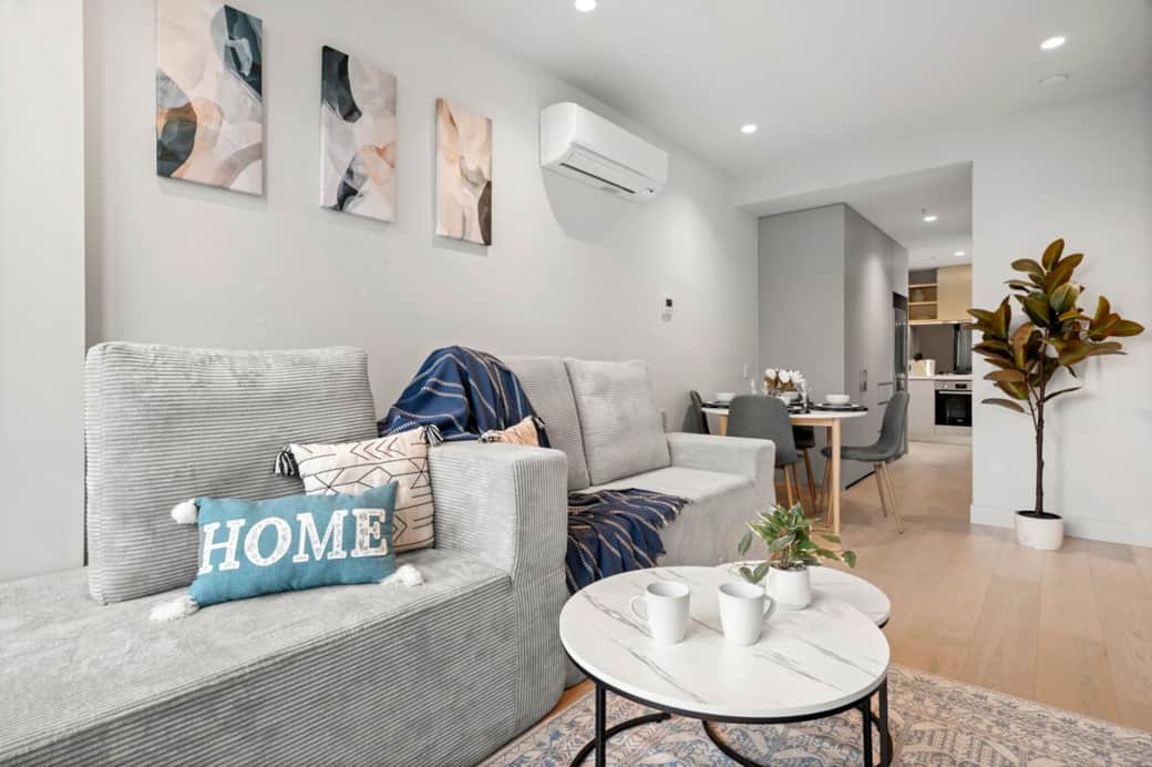 The living room is bright, modern, and designed for comfort — featuring a cosy sofa, Smart TV, and a light-filled open-plan layout that flows into the dining and kitchen area. It’s the perfect space to unwind after a day exploring Melbourne