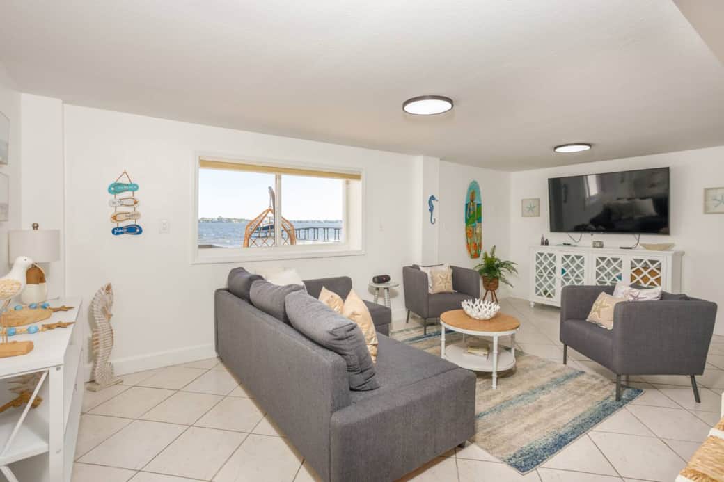 Cozy living room featuring a big sectional, accent chairs, Smart TV, and peaceful water views.