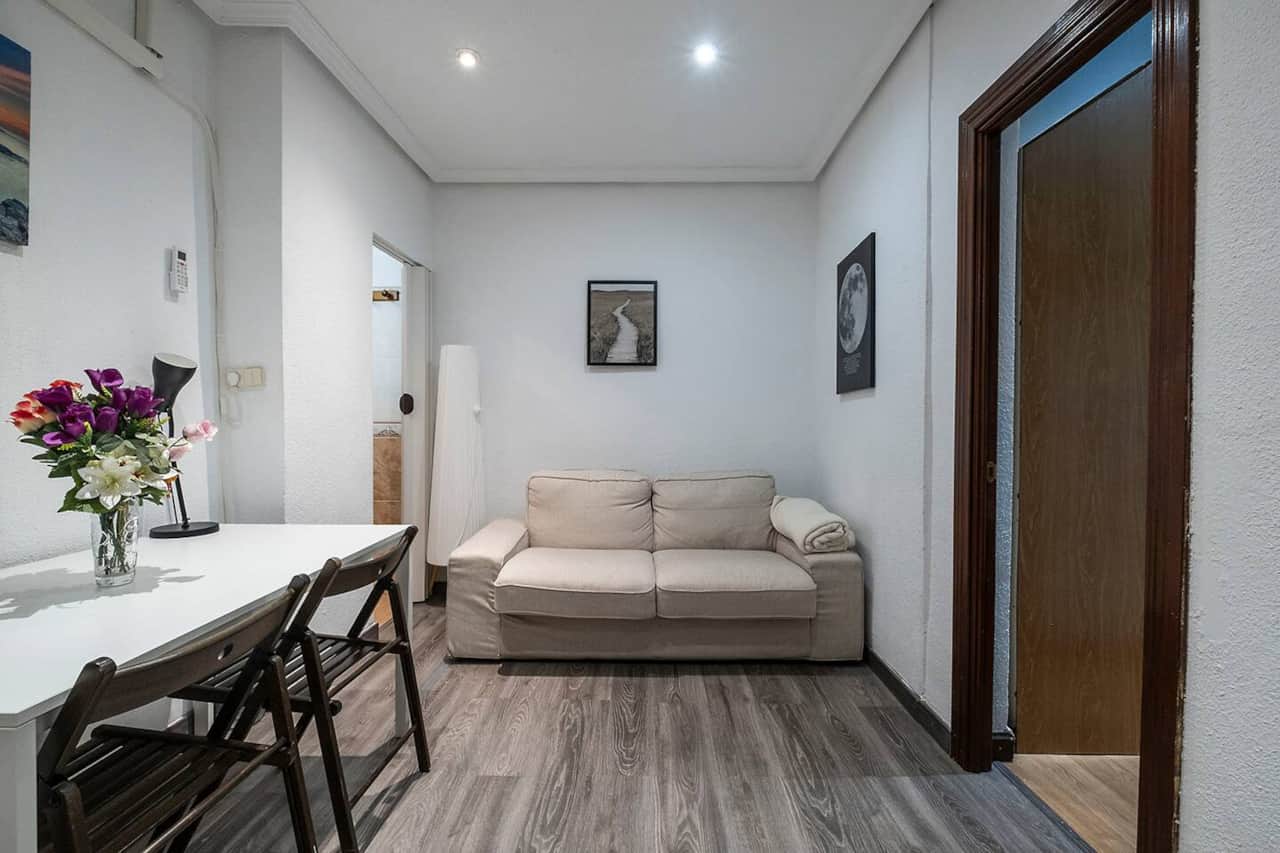 Salón con sofá cama, mesa de comedor y suelo laminado