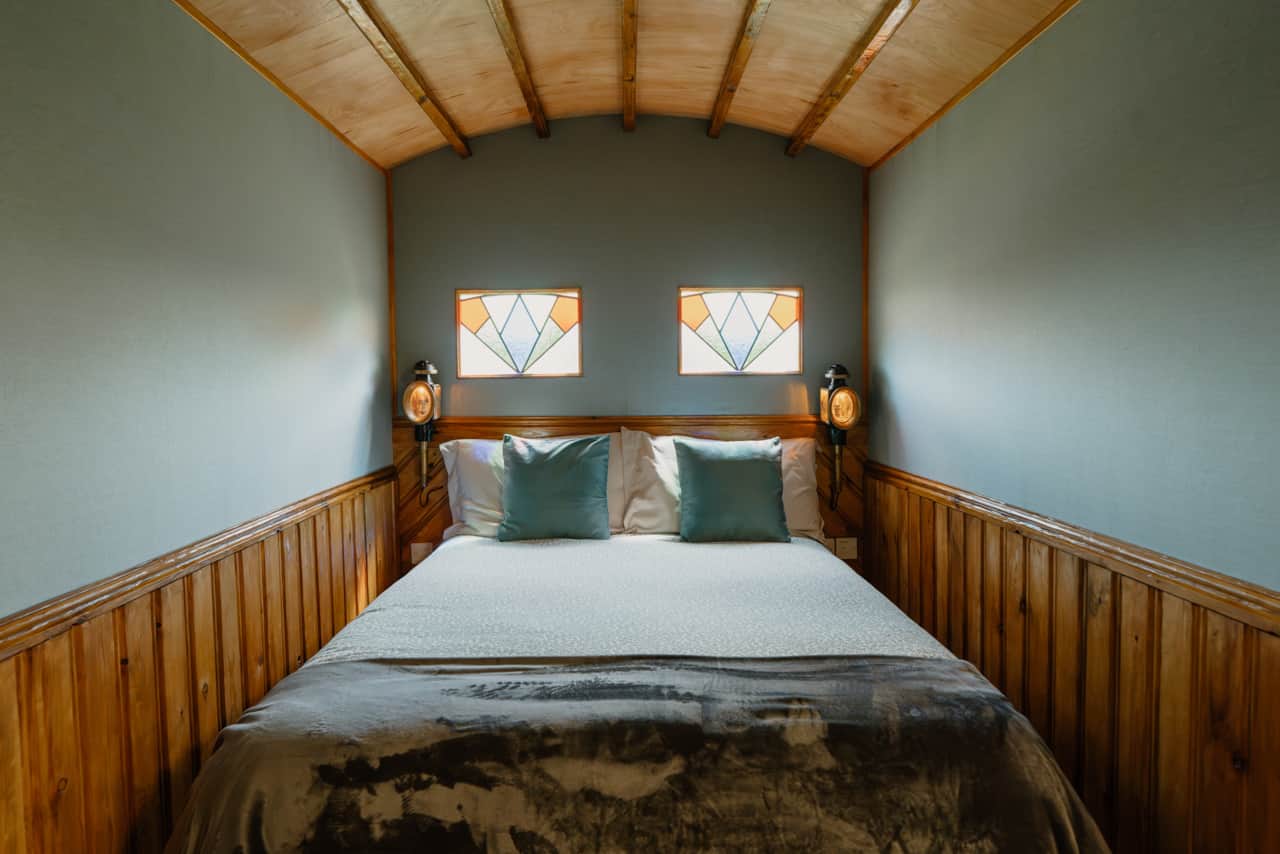 The Cosy Nest Hut double bed with reclaimed stained glass windows above.