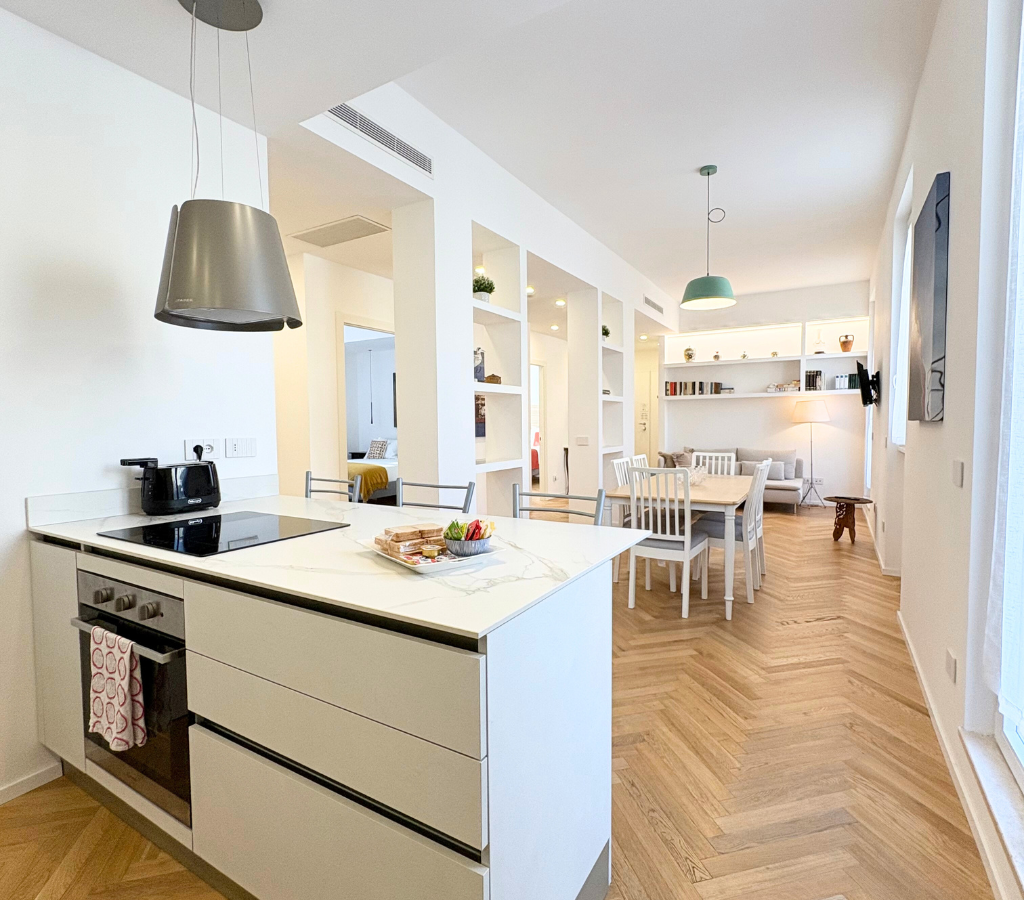 Zona giorno open-space con cucina attrezzata, smart TV, e aria condizionata.