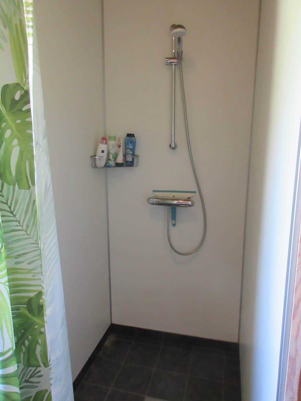 Im Badezimmer gibt es eine Dusche mit Kalt- und Warmwasser sowie einen Bodenablauf. Der gesamte Sanitärbereich ist gefliest und mit einer Fußbodenheizung ausgestattet.