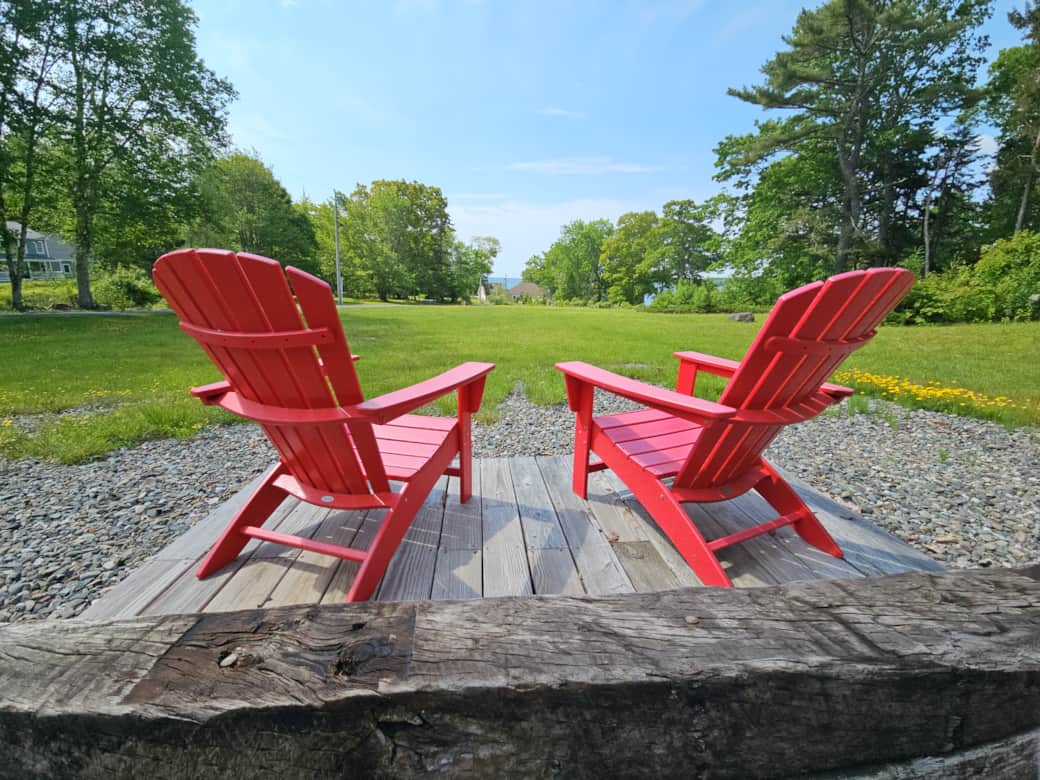 Unwind on classic red Adirondack chairs on the deck overlooking the open lawn