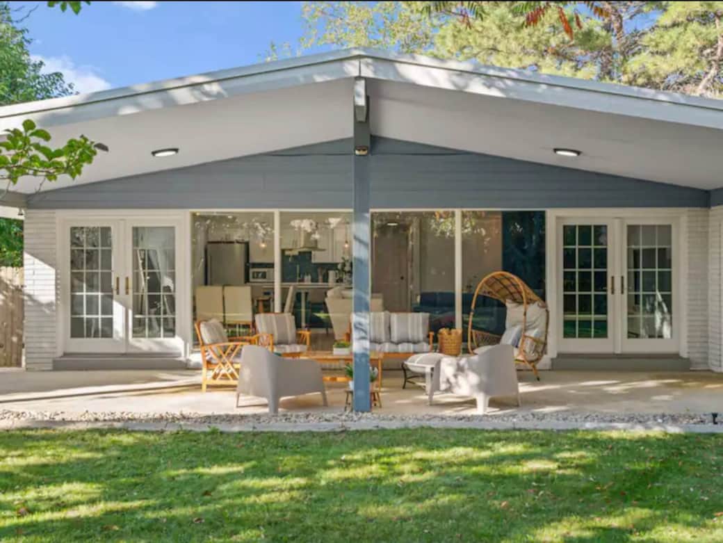 Loved by guests for comfort, location, and family-friendly space. This bright patio features wall-to-wall glass showcasing the living room, kitchen, and dining area inside, with a cozy outdoor seating set perfect for relaxing and gathering.
