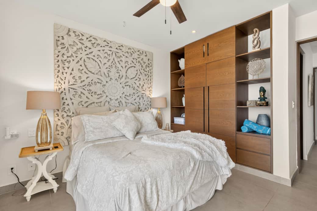 Ocean-view bedroom with balcony, AC, ceiling fan, wardrobe, beach towels, and bedside outlets.