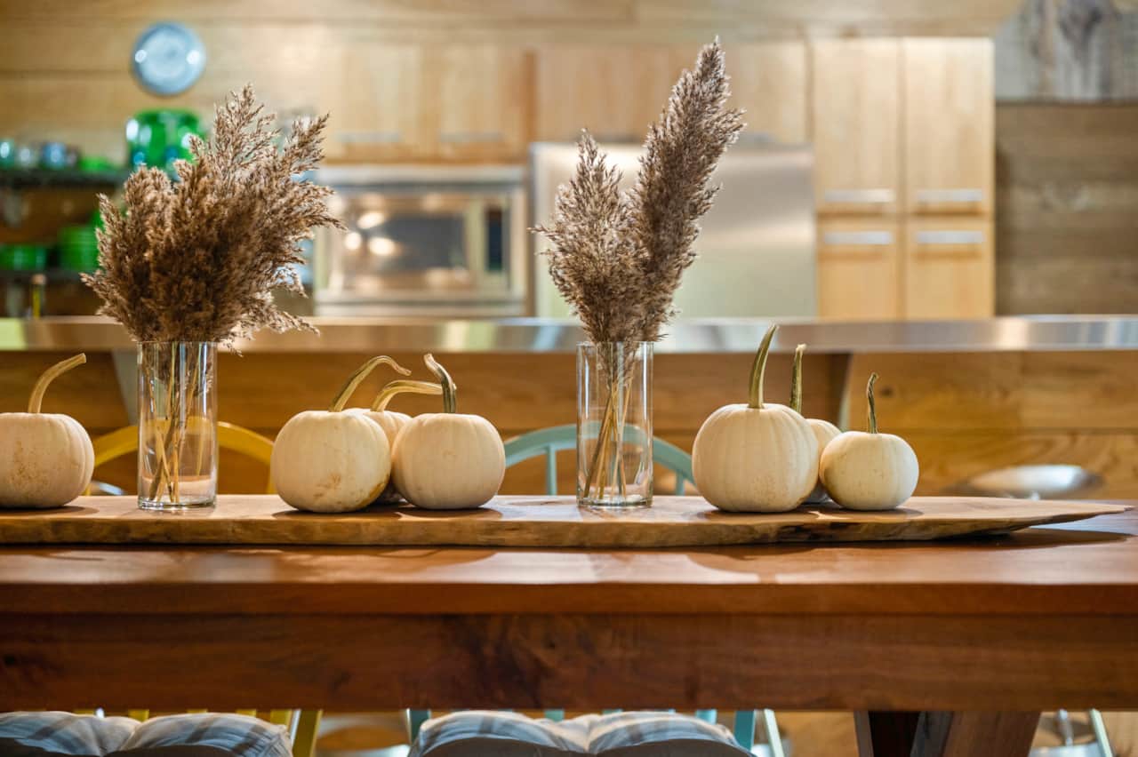 Custom black walnut dining table staged for the fall in white pumpkins and pompas grasses.  Enjoy seasonal decorations throughout the cabin.
