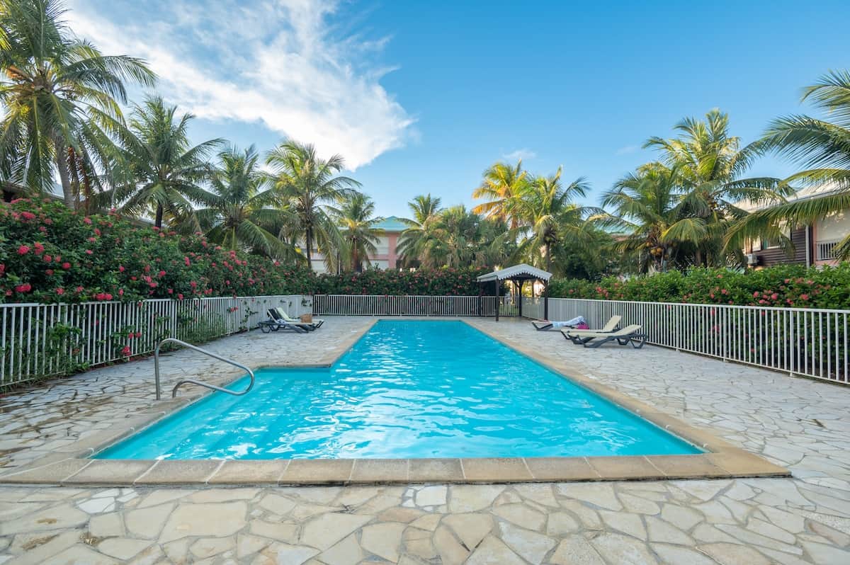 Piscine Crystal Beach avec palmiers, ciel bleu et résidence sécurisée