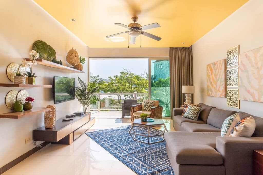 The sun-filled living room opens onto a private balcony overlooking the swimming pool and garden