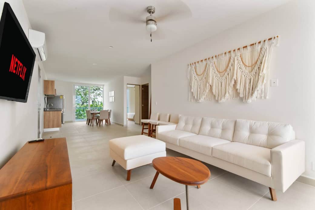 Living room with 50" Smart TV, A/C, couch, and balcony with ocean views.