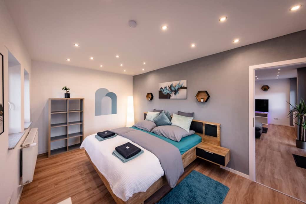 Modernes Schlafzimmer mit warmem Charme - die Bettanlage mit integriertem Nachttisch und indirekter Beleuchtung laden zum Entspannen vor dem Einschlafen ein