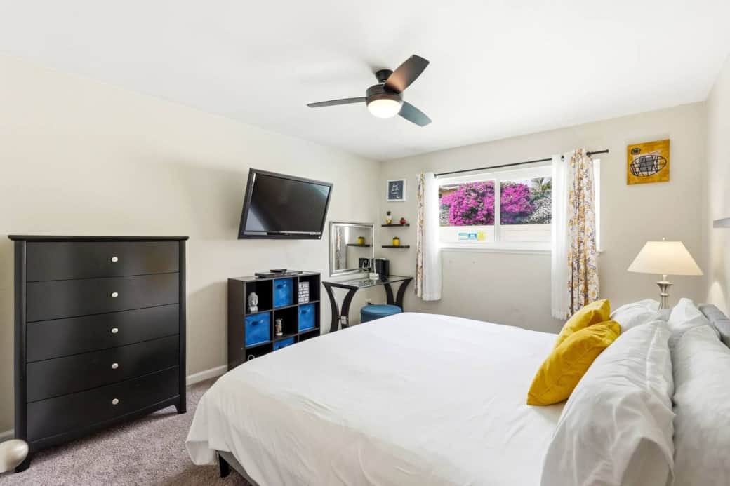 This room includes a wall-mounted TV and a dresser, perfect for keeping belongings organized.