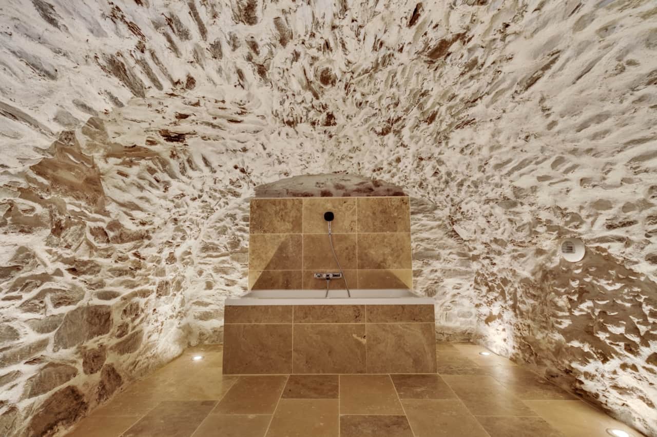 Baignoire nichée sous la voûte en pierre de l'ancienne cave du chalet.