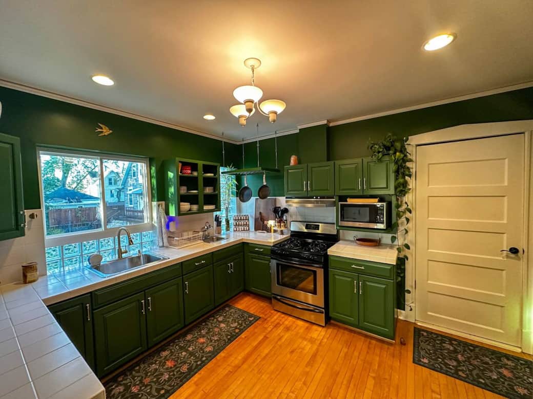 Charming green kitchen with all the essentials for a home-cooked meal—gas stove, microwave, spices, and cookware. Enjoy morning coffee by the window or unwind while preparing dinner in this cozy, inviting space that feels both stylish and personal.