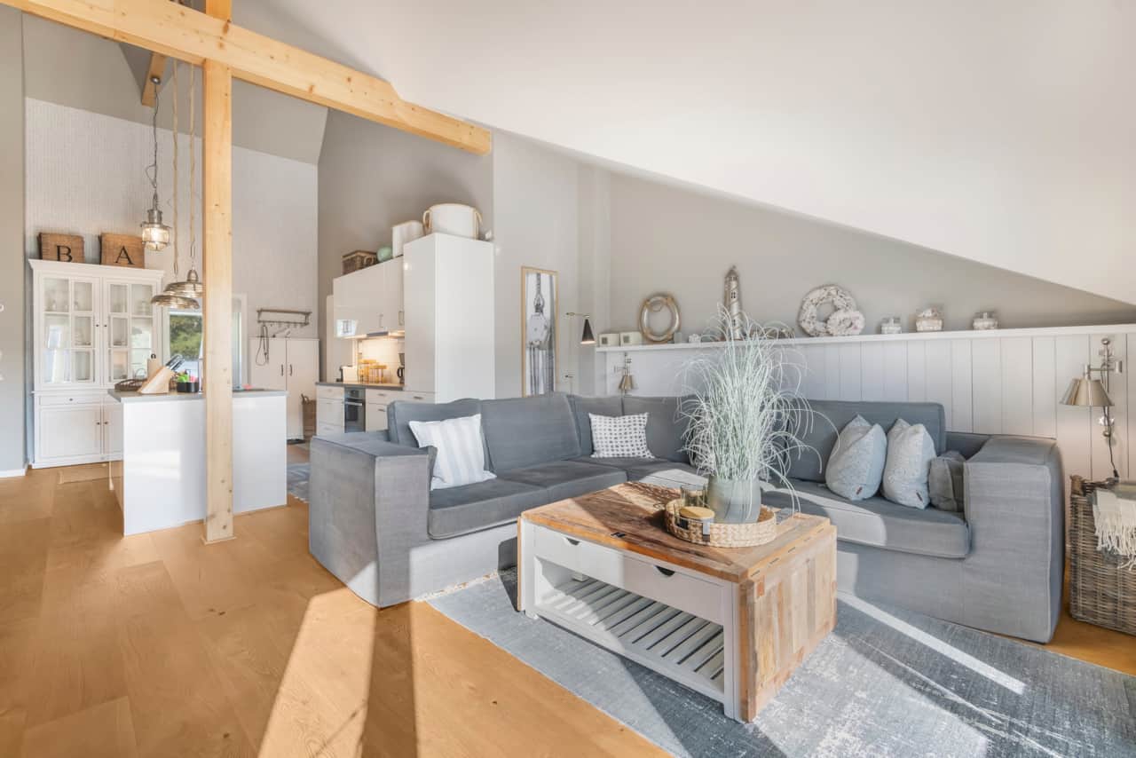 Stilvoller Sitzbereich mit grauem Sofa, hellen Holzmöbeln und dekorativen Wohnaccessoires.