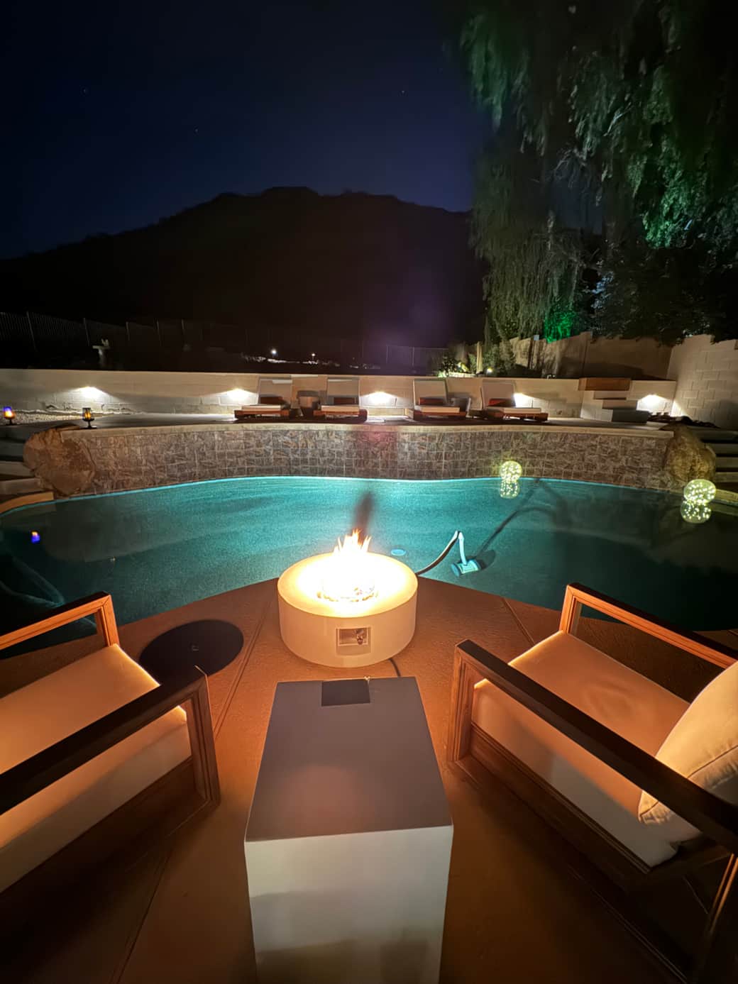 Night view of pool, fire pit, lounging deck