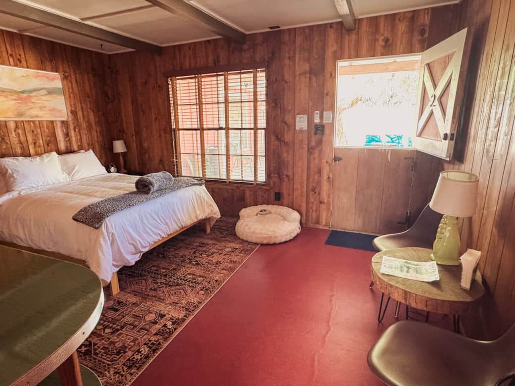 Cozy queen bed with window view, dog bed, and desert-inspired decor