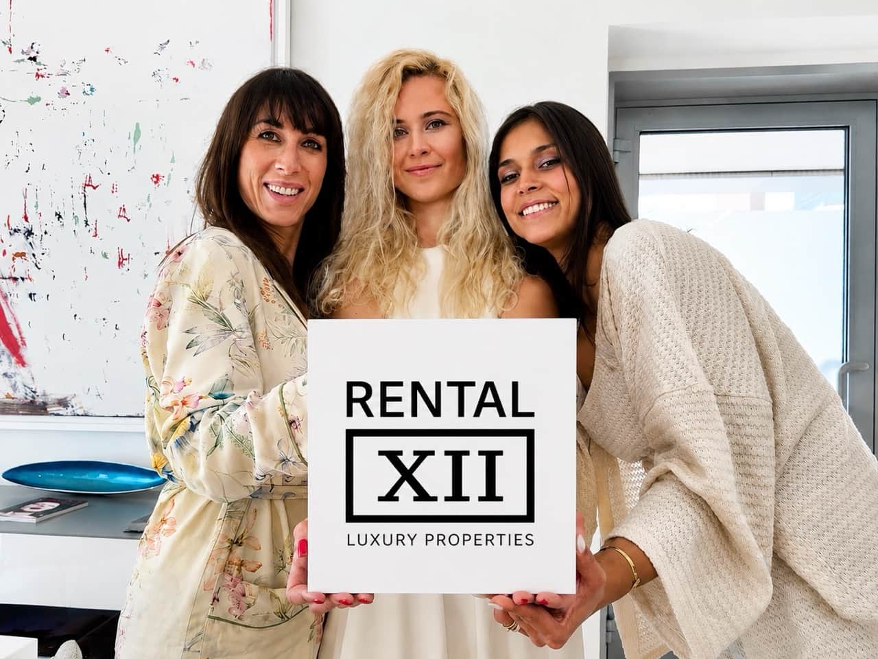 Anastasia Duke, Floriana and Kristina laughing as they hold the RENTAL12 logo at the Olbia office