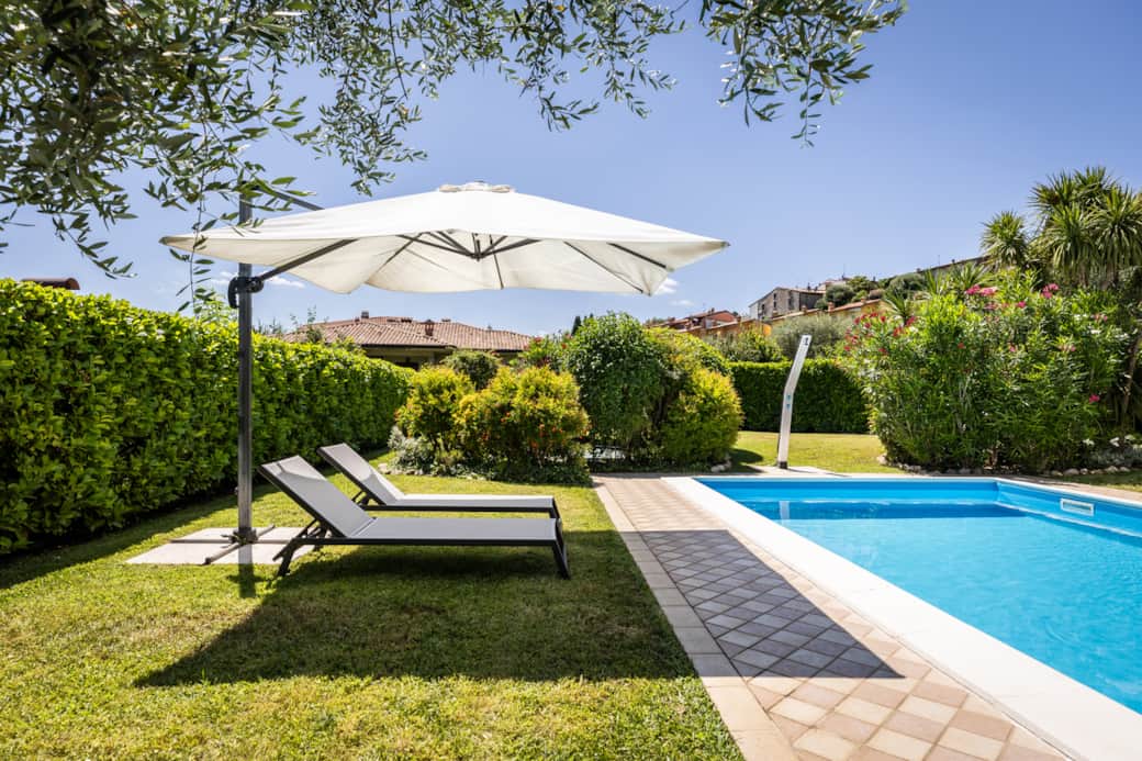 Entspannungsbereich mit Außendusche, Sonnenliegen und hohen Hecken für maximale Privatsphäre.