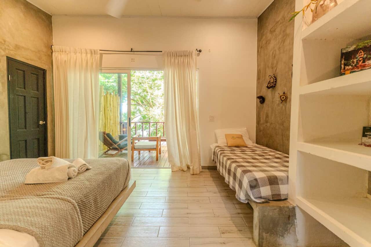 Puerta corrediza de vidrio de la Deluxe Suite a una terraza de madera entre árboles, Saboga Lodge