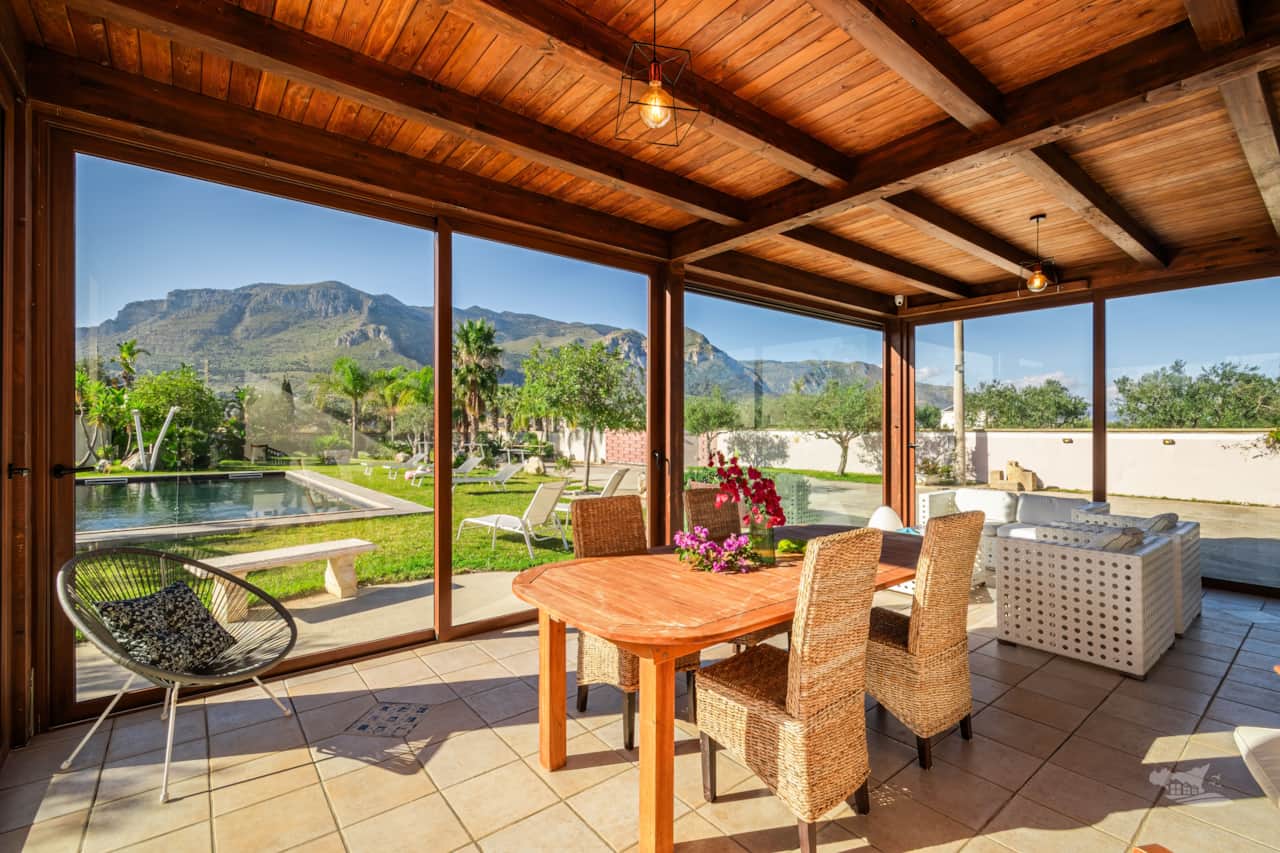 Enjoy enchanting views from this glass-enclosed patio, overlooking a tranquil pool and mountains.