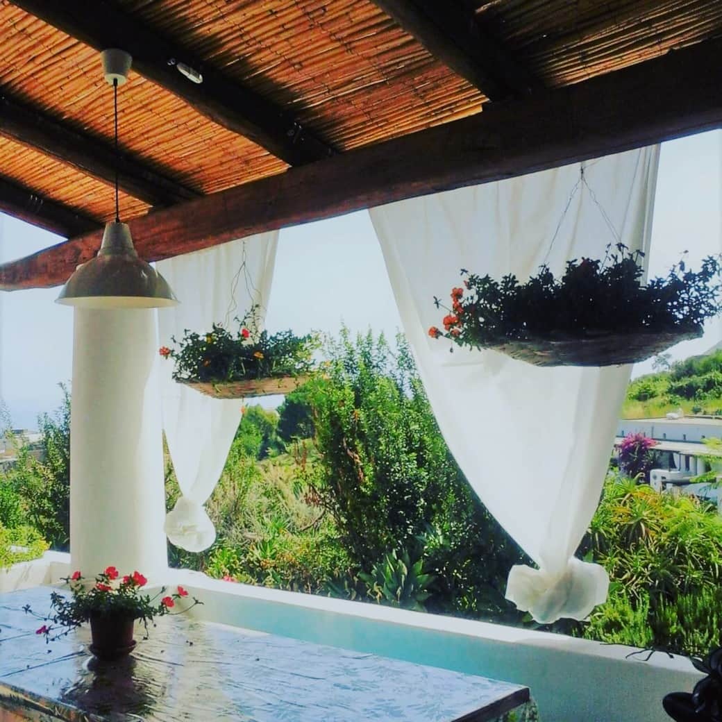 Veranda ombreggiata con tende bianche a Malfa, Salina, perfetta per il relax estivo. Veranda ombreggiata con tende bianche a Malfa, Salina, perfetta per il relax estivo.