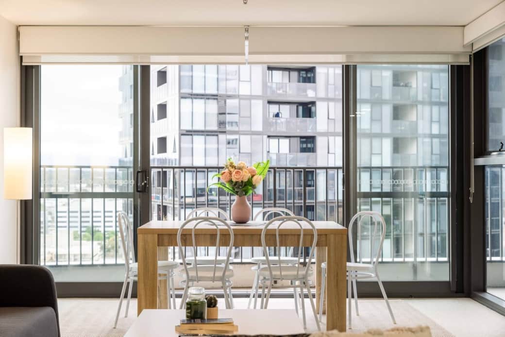 Step into a world of elegance with our dining area. The natural light streaming through the floor-to-ceiling windows highlights the warm tones of the wooden table. Enjoy meals with a cityscape, or simply bask in the comfort of this inviting space