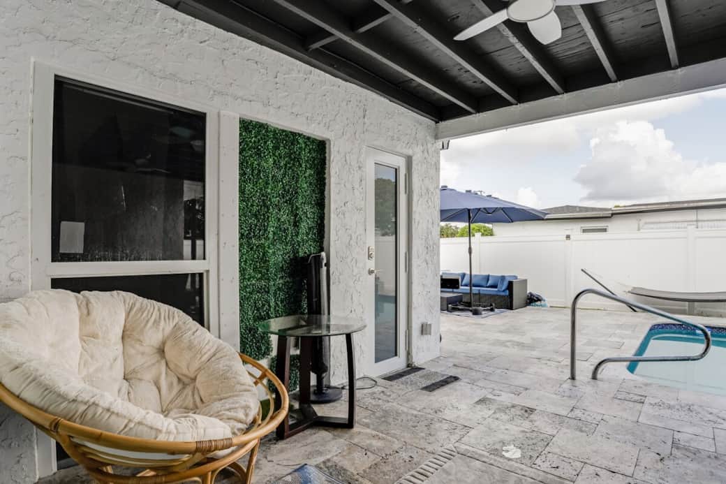 Tucked-away covered patio retreat with lounge seating, offering a shaded escape just off the pool—perfect for unwinding, reading, or enjoying a quiet moment outdoors.