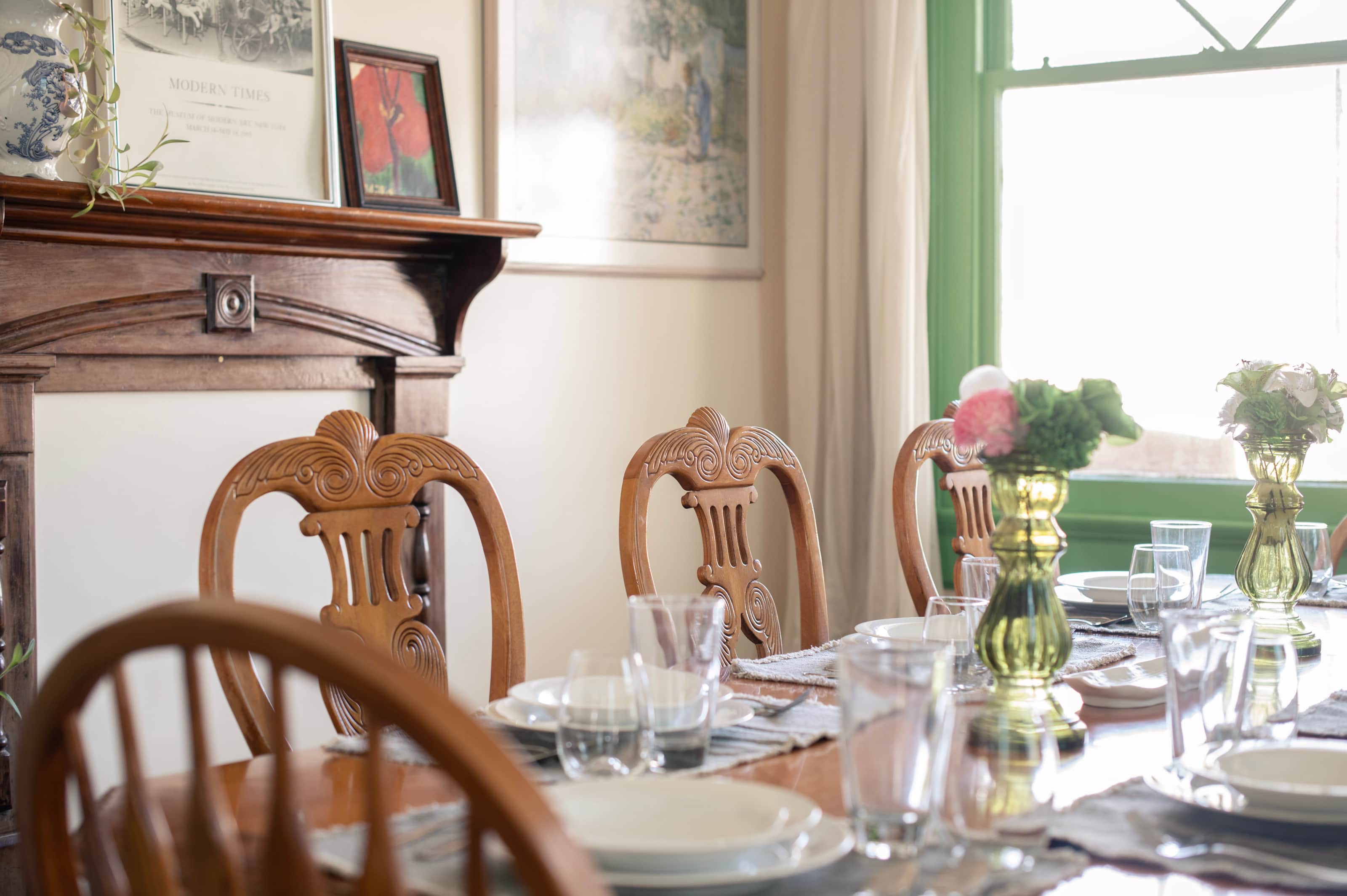 A dining table set with plates, glasses, and vases in a room with a window.