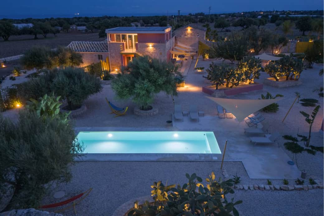 Vista aerea della piscina e del giardino con l'illuminazione notturna