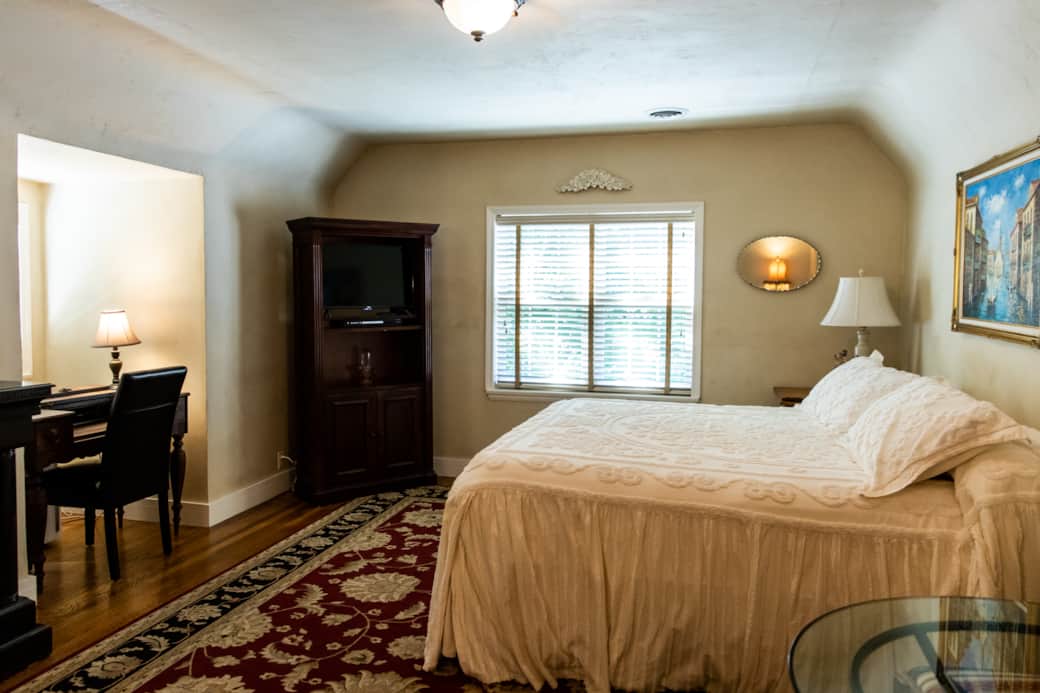 Spacious king bedroom—luxury bedding, vintage touches, and natural light