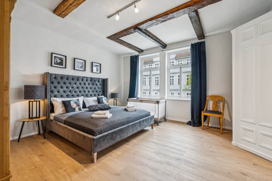 Großes Zimmer mit Kingsize-Bett, Design-Akzenten und viel Licht durch hohe Fenster.