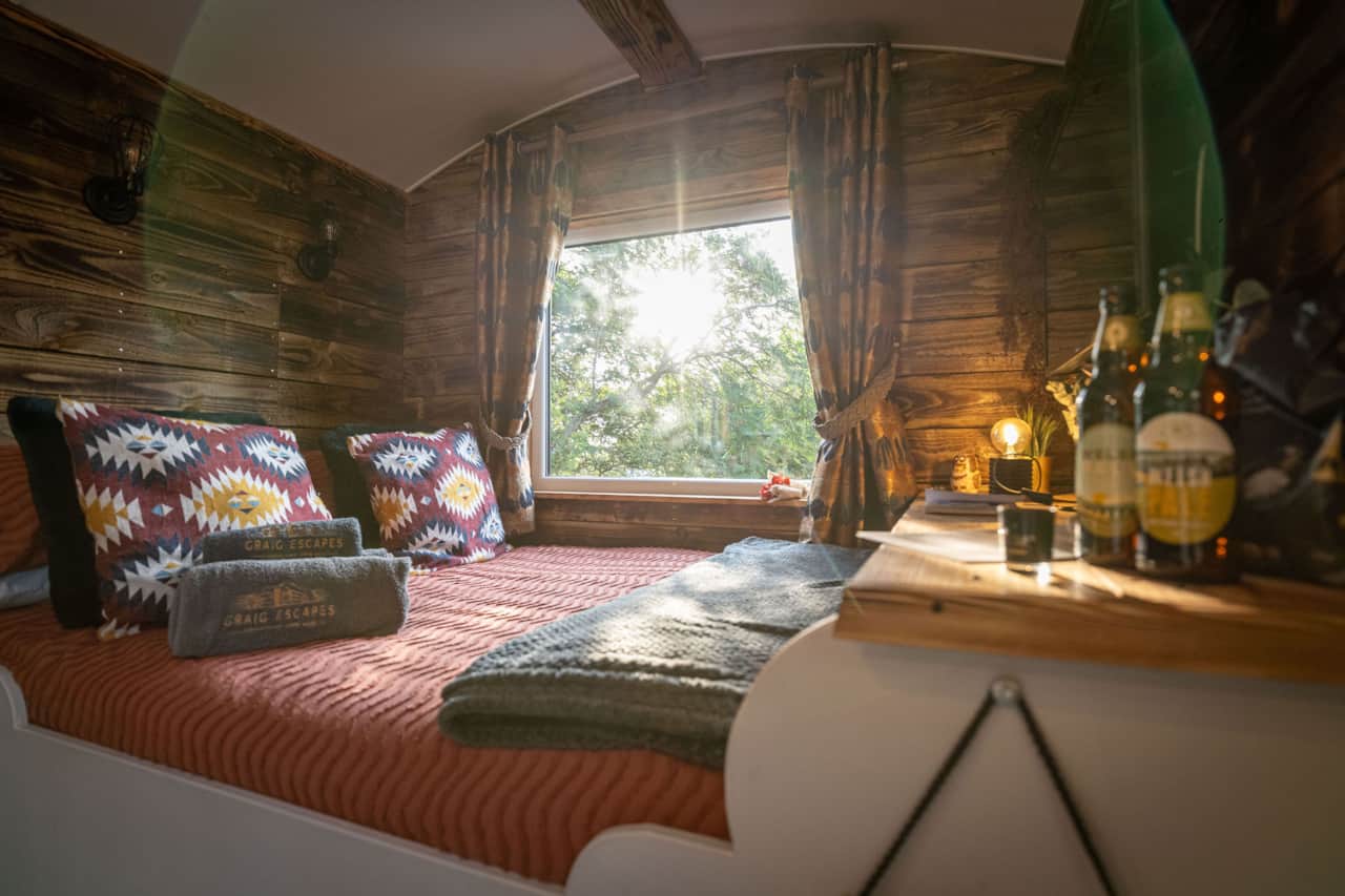 Intimate sleeping area with bright window and plush pillows.