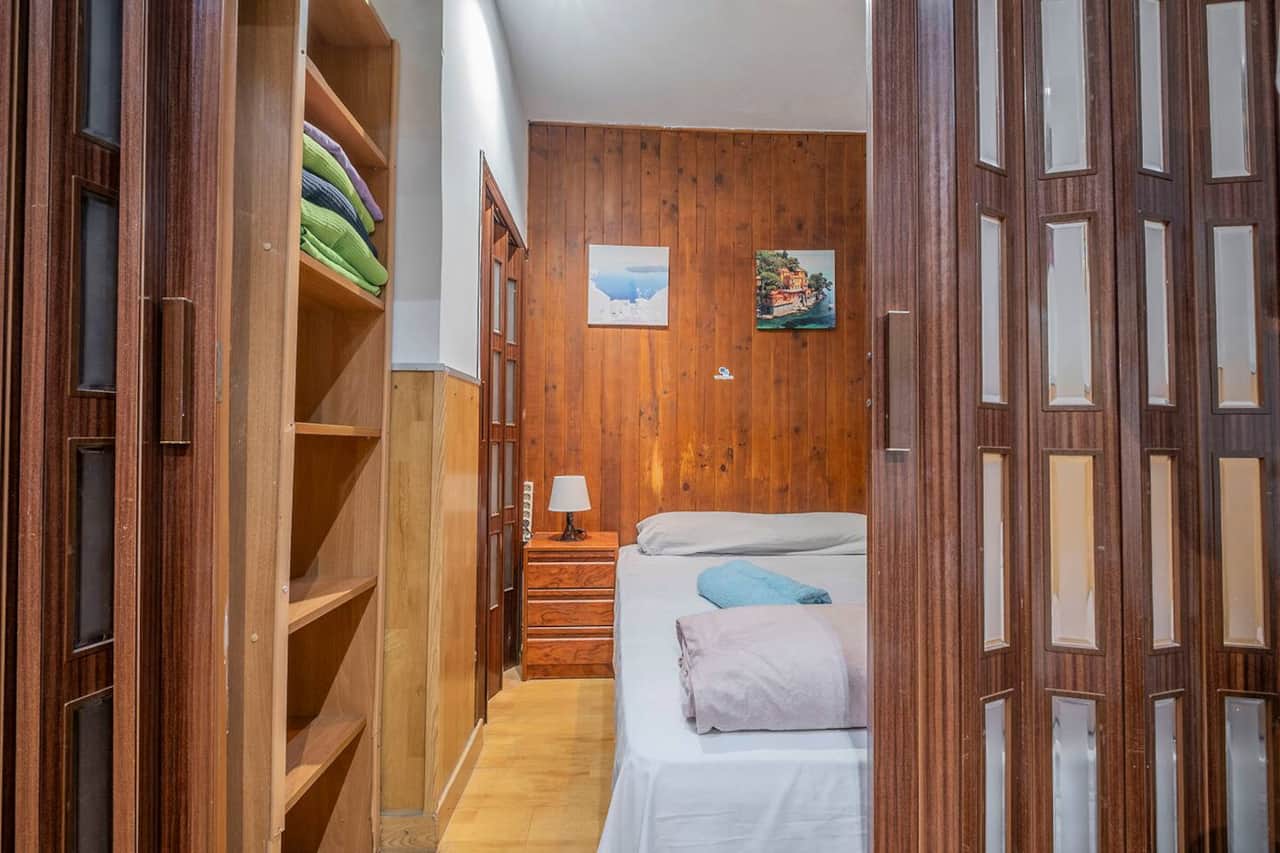 Dormitorio con armario abierto y ropa de cama preparada