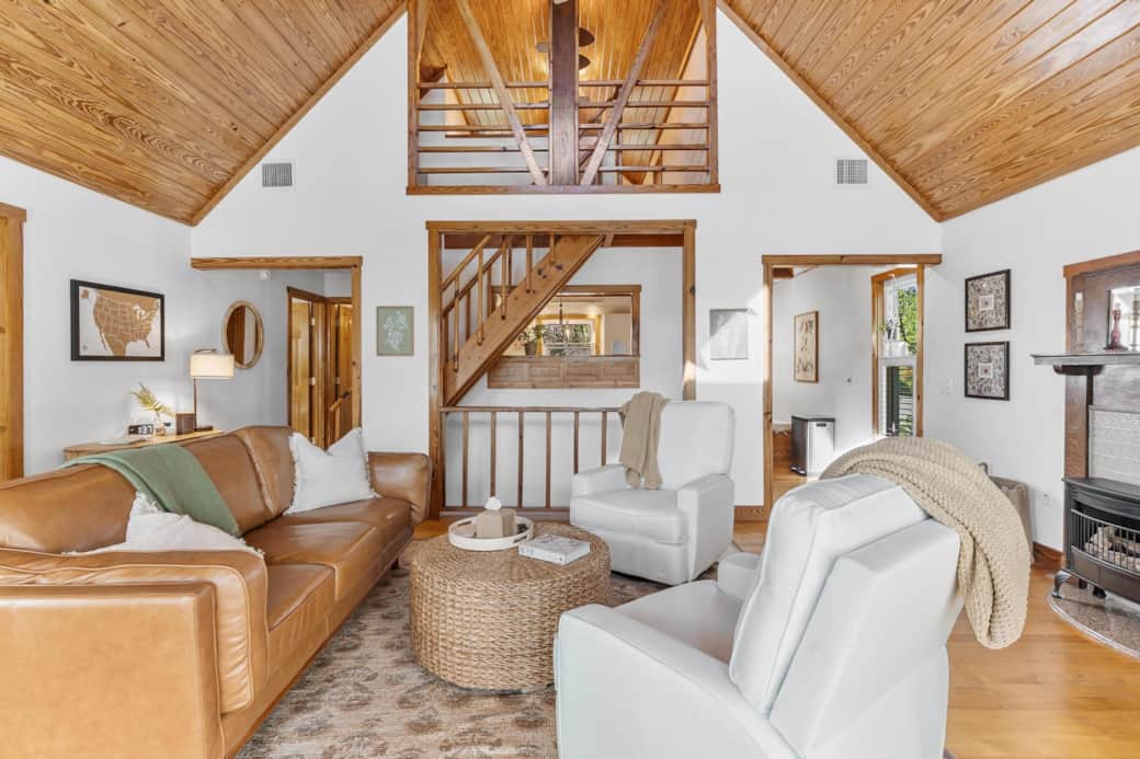 Open living room with a fireplace, leather sofa and recliner/swivel chairs.