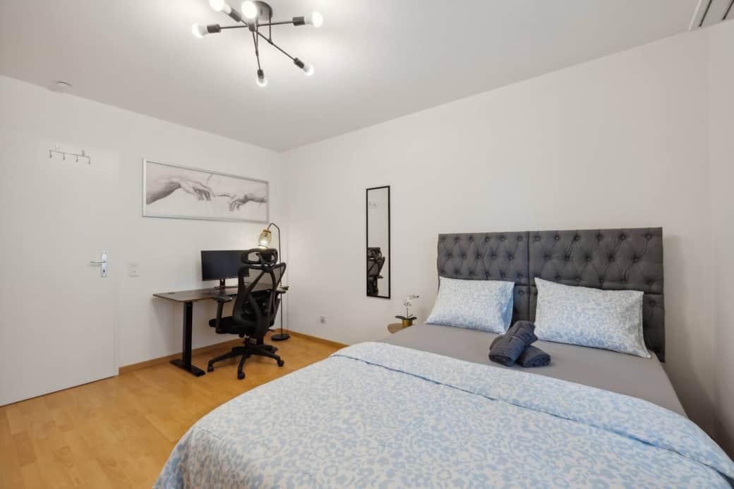 Work-ready setup: ergonomic chair, 24'' monitor and plenty of daylight right next to your bed.