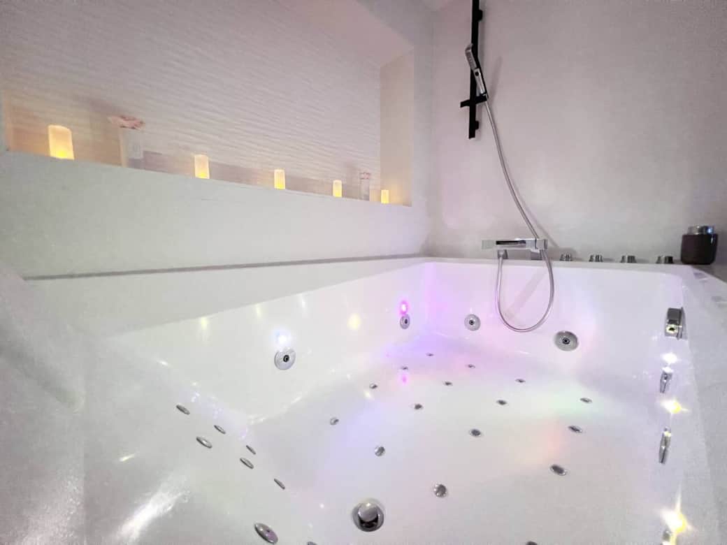 Un espace spa privé avec jets massant, idéal pour un moment de détente après une journée bien remplie. Les bougies disposées autour du jacuzzi renforcent l’ambiance cocooning.