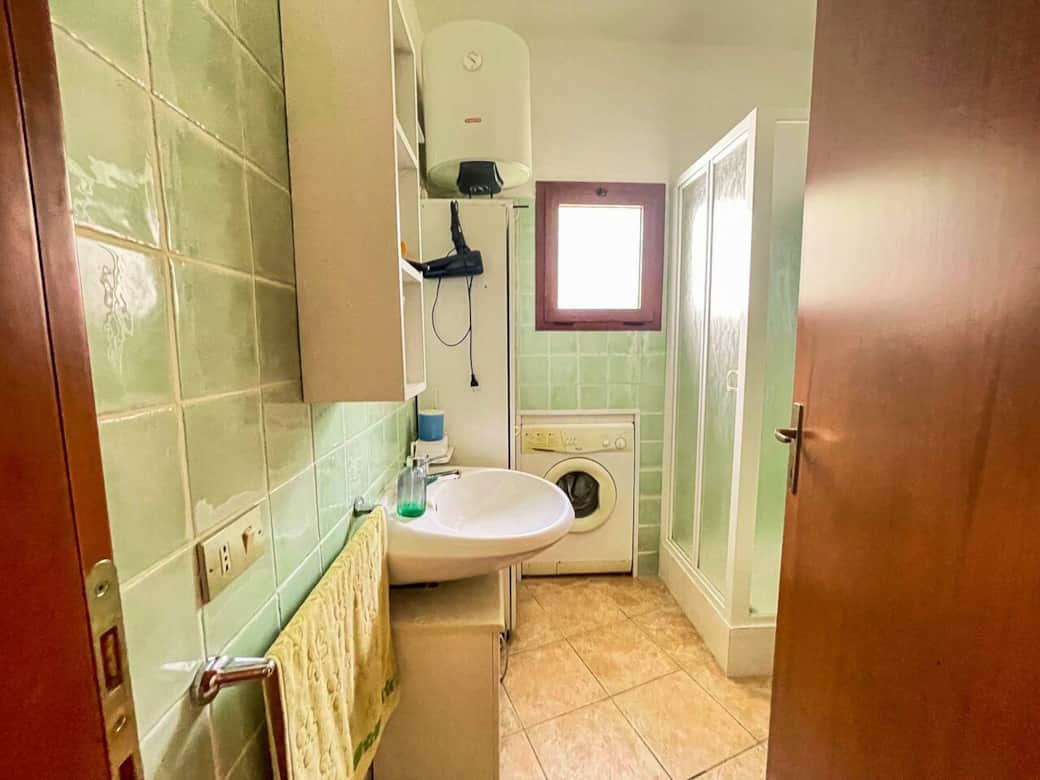 Bagno completo con doccia e lavatrice, comodo e funzionale per soggiorni lunghi. L’ambiente è pratico e ben illuminato dalla luce naturale.
