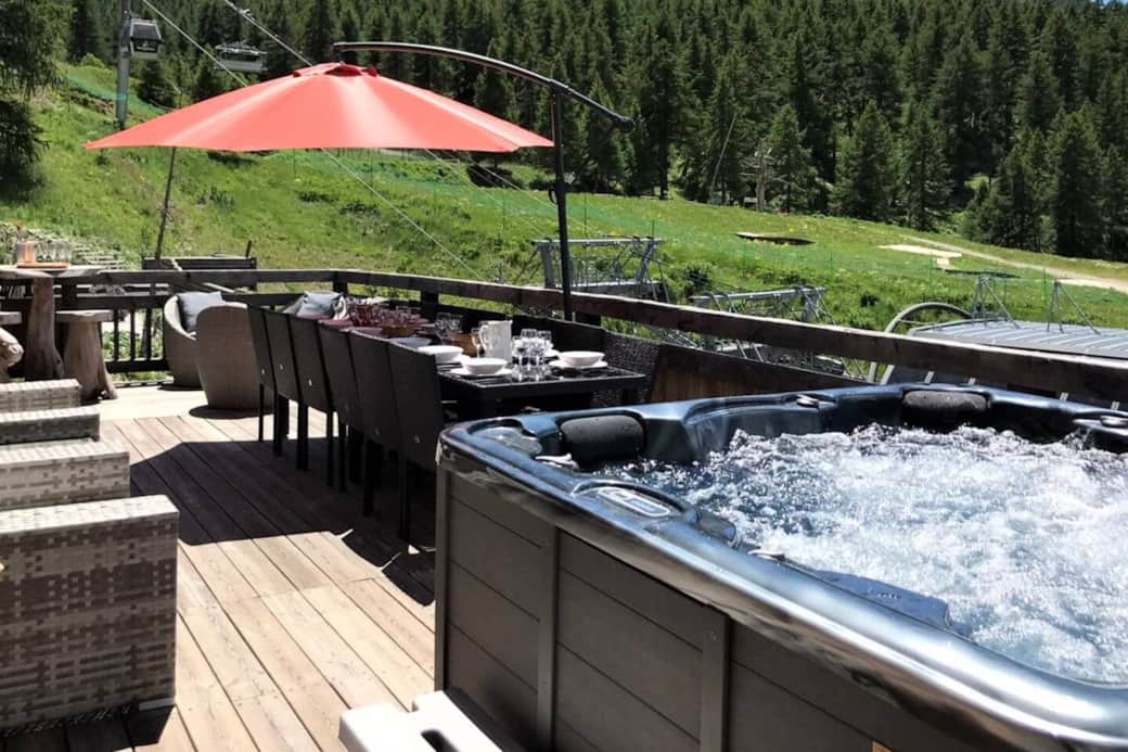 La terrasse avec le barbecue, la table pour manger dehors, le jacuzzi et le salon de jardin