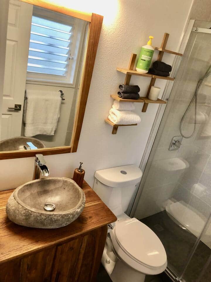 Newly remodeled bathroom with a natural teak vanity and a stone sink.