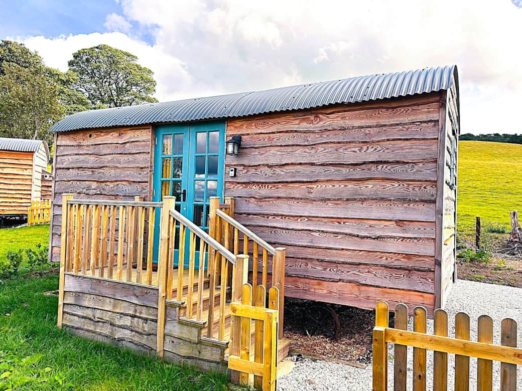 Rustic timber shepherd hut with private deck and peaceful countryside setting.