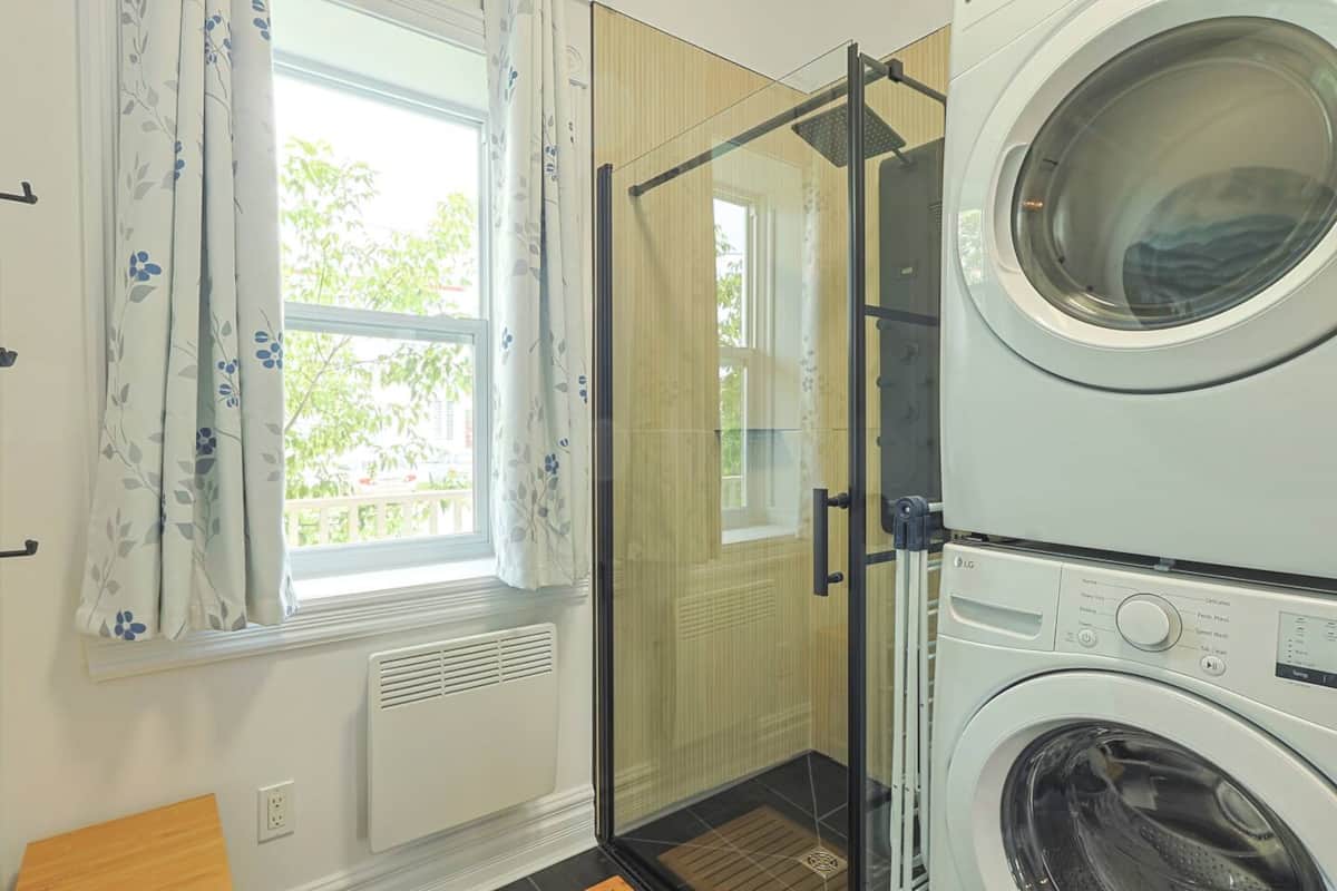 Espace lumineux tout-en-un avec douche vitrée moderne et buanderie discrète intégrée.