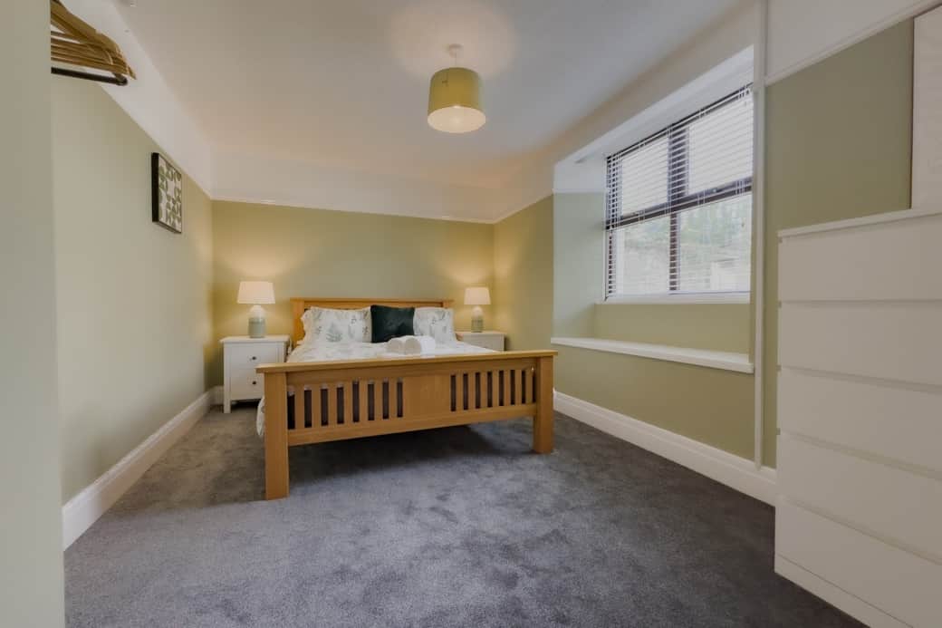 Masterbedroom with kingsize bed, chest of drawers and hanging rail