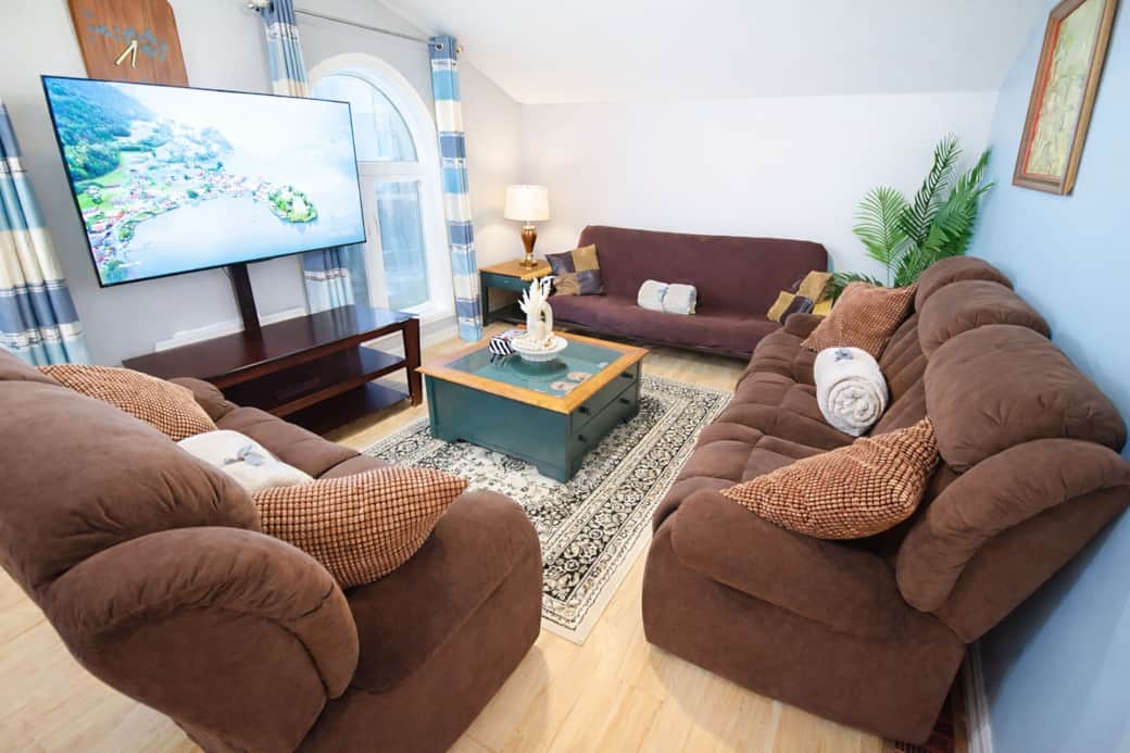 Open-concept living space featuring recliner sofas, large windows, and a 55” smart TV Open-concept living space featuring recliner sofas, large windows, and a 55” smart TV