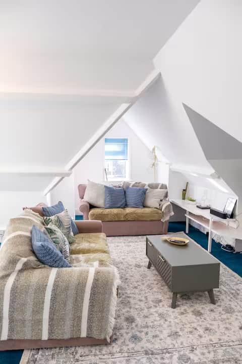 Bright, stylish loft living area with comfortable sofas, Smart TV, and coffee table Bright, stylish loft living area with comfortable sofas, Smart TV, and coffee table