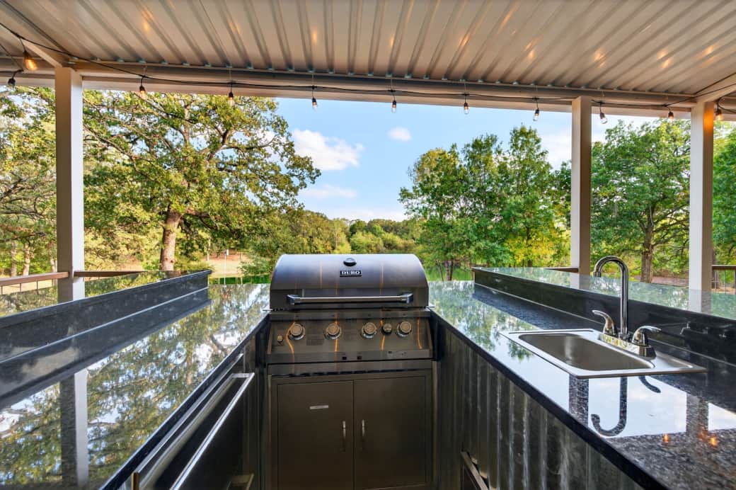 Outdoor kitchen with grill, built-in beverage fridge, and sink.