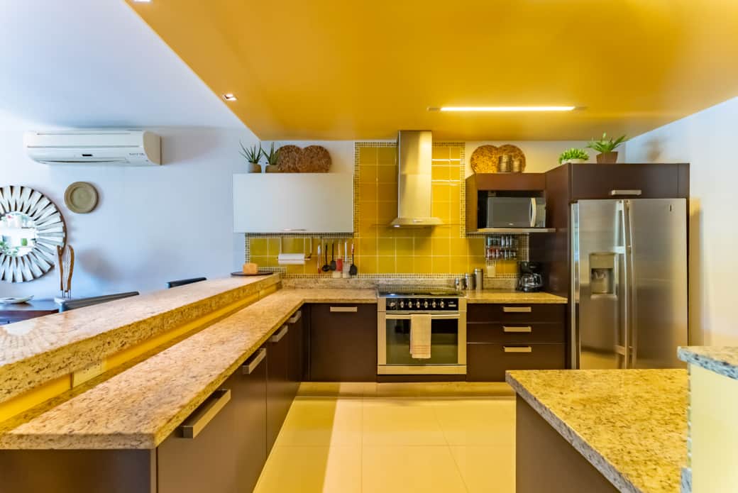 Spacious kitchen with many small appliances. Cupboards are stocked with essentials