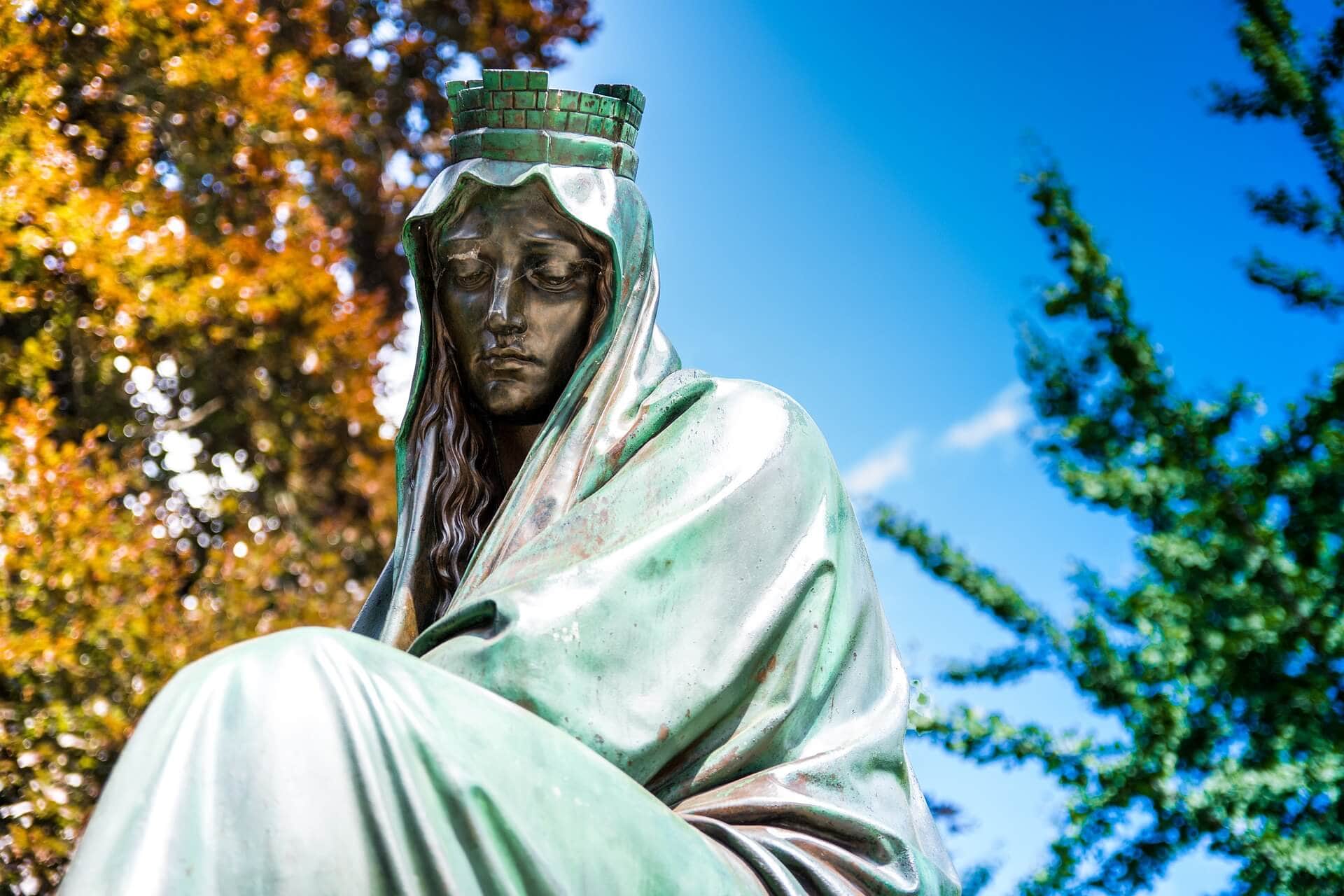 Lutherdenkmal in Worms mit Bronzestatue vor blauem Himmel und herbstlichen Bäumen.